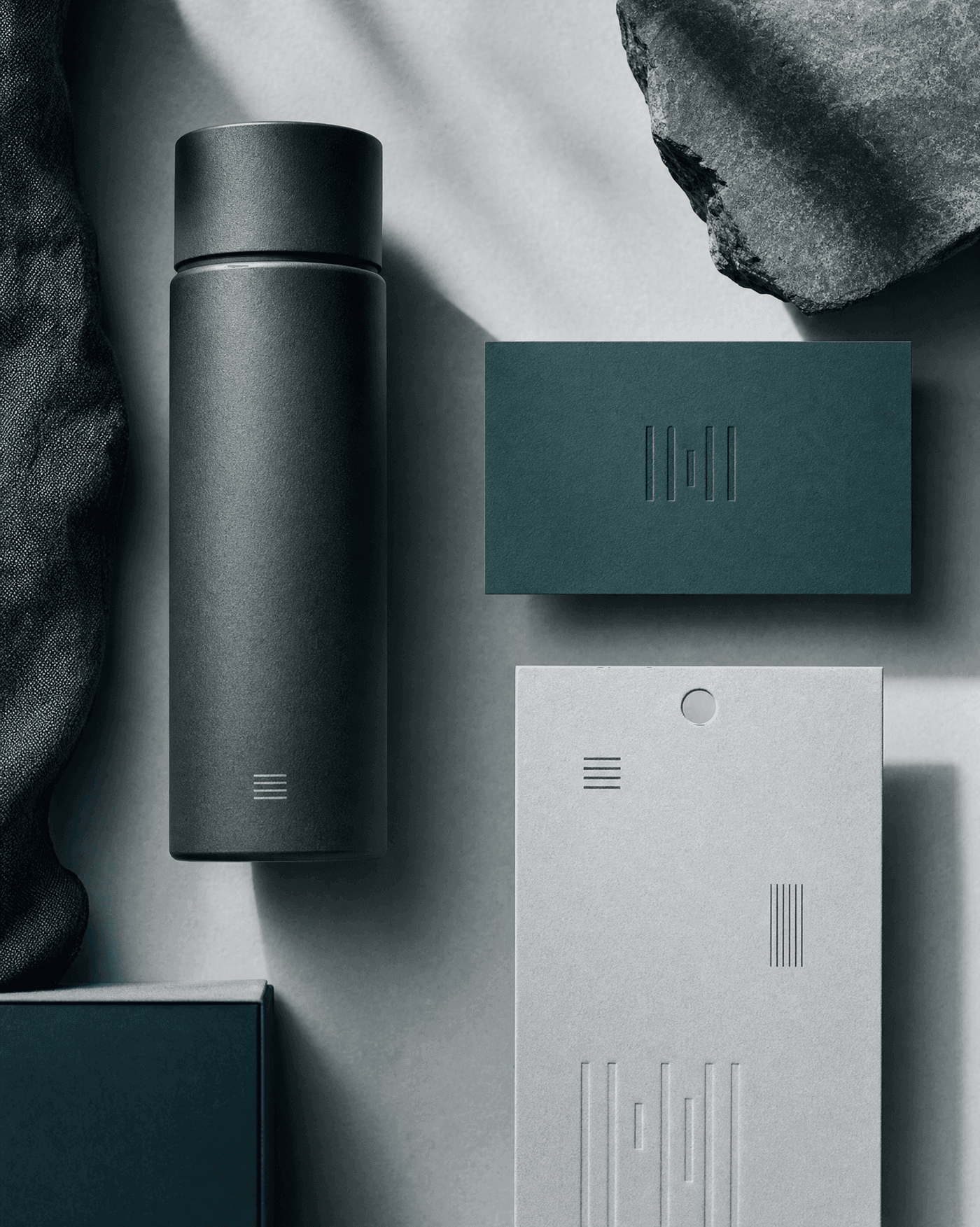 A premium product, a business card, and a printed tag, each carrying a discreet wordmark, the surfaces a brand name lives on