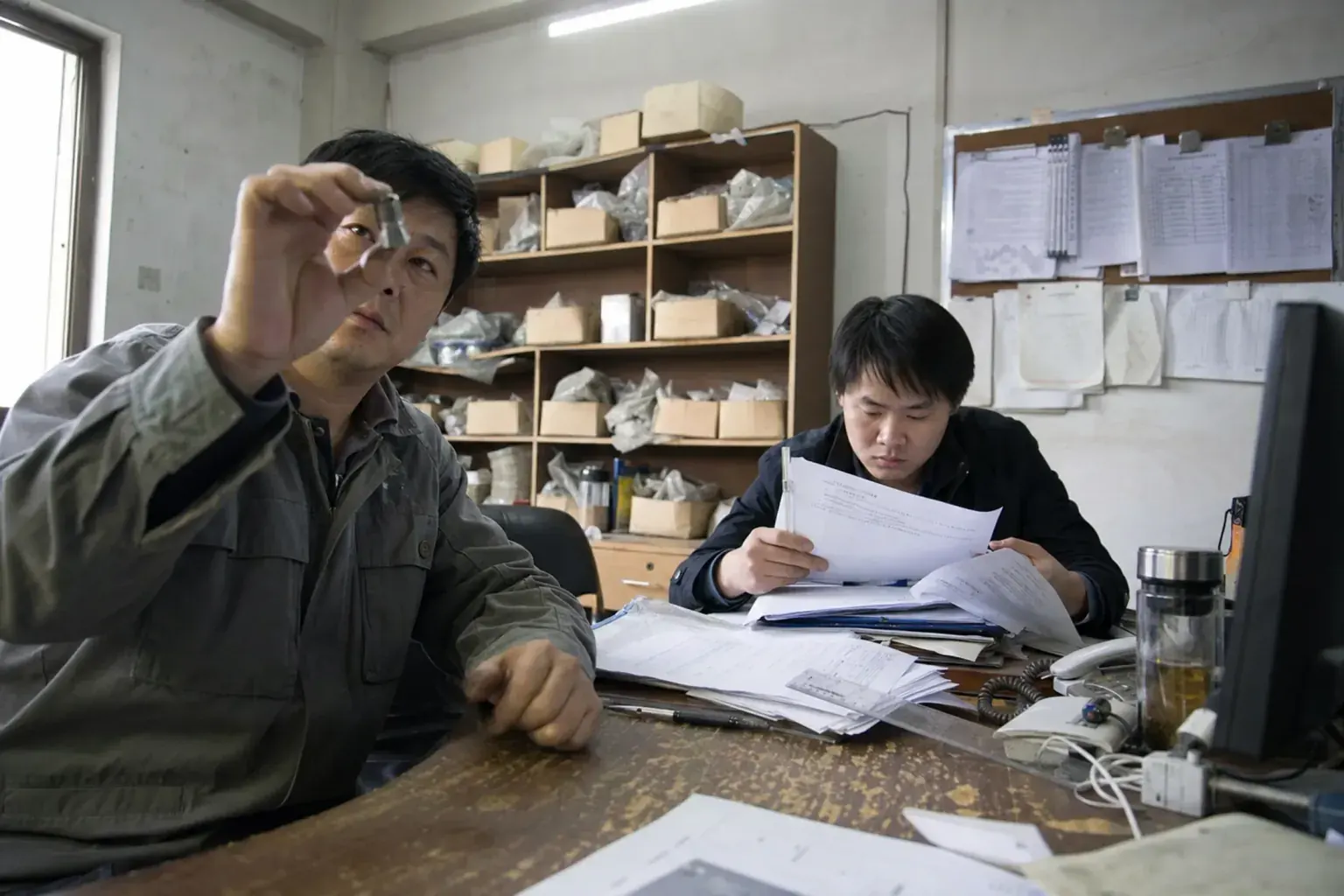 A Chinese factory's compliance team checking a product sample against certification paperwork before an overseas launch