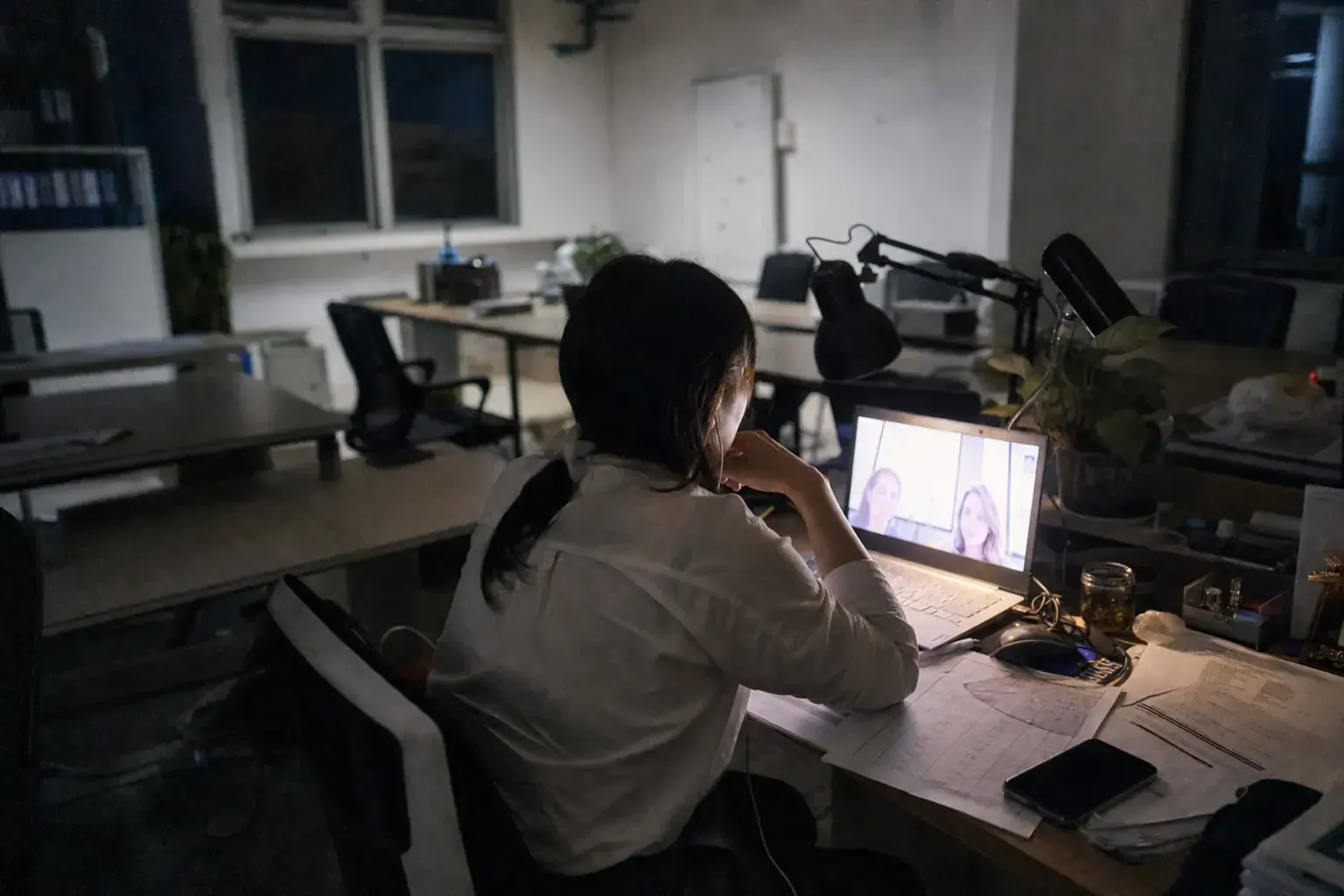 A Chinese export manager working late on a video call with European buyers, price sheets spread across the desk
