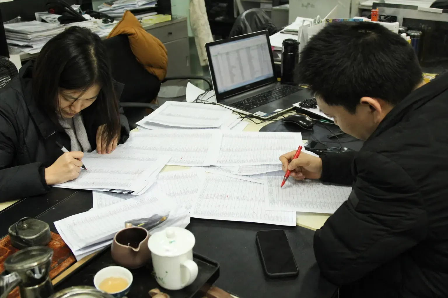 Chinese export staff cutting a long list of candidate overseas distributors down with a red pen
