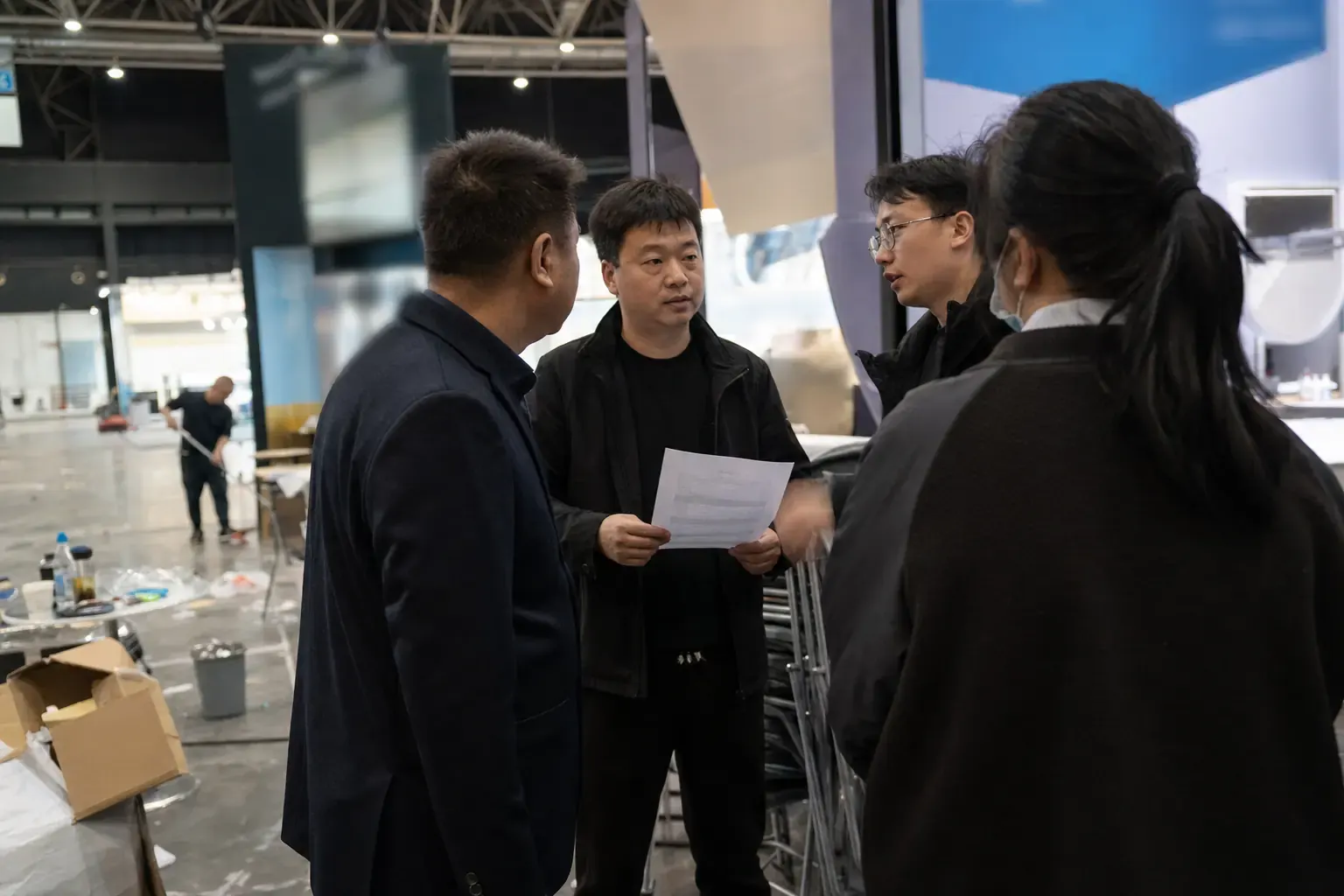 A Chinese exhibitor team briefing at their stand in an empty European fair hall before opening