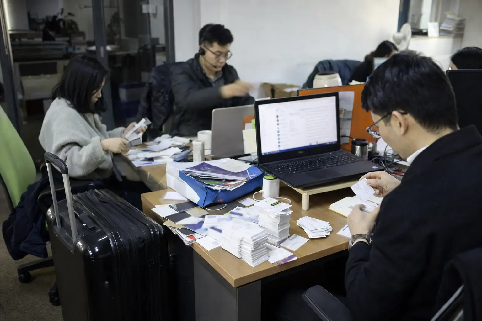 A Chinese export team back in the office working through business cards collected at an overseas fair