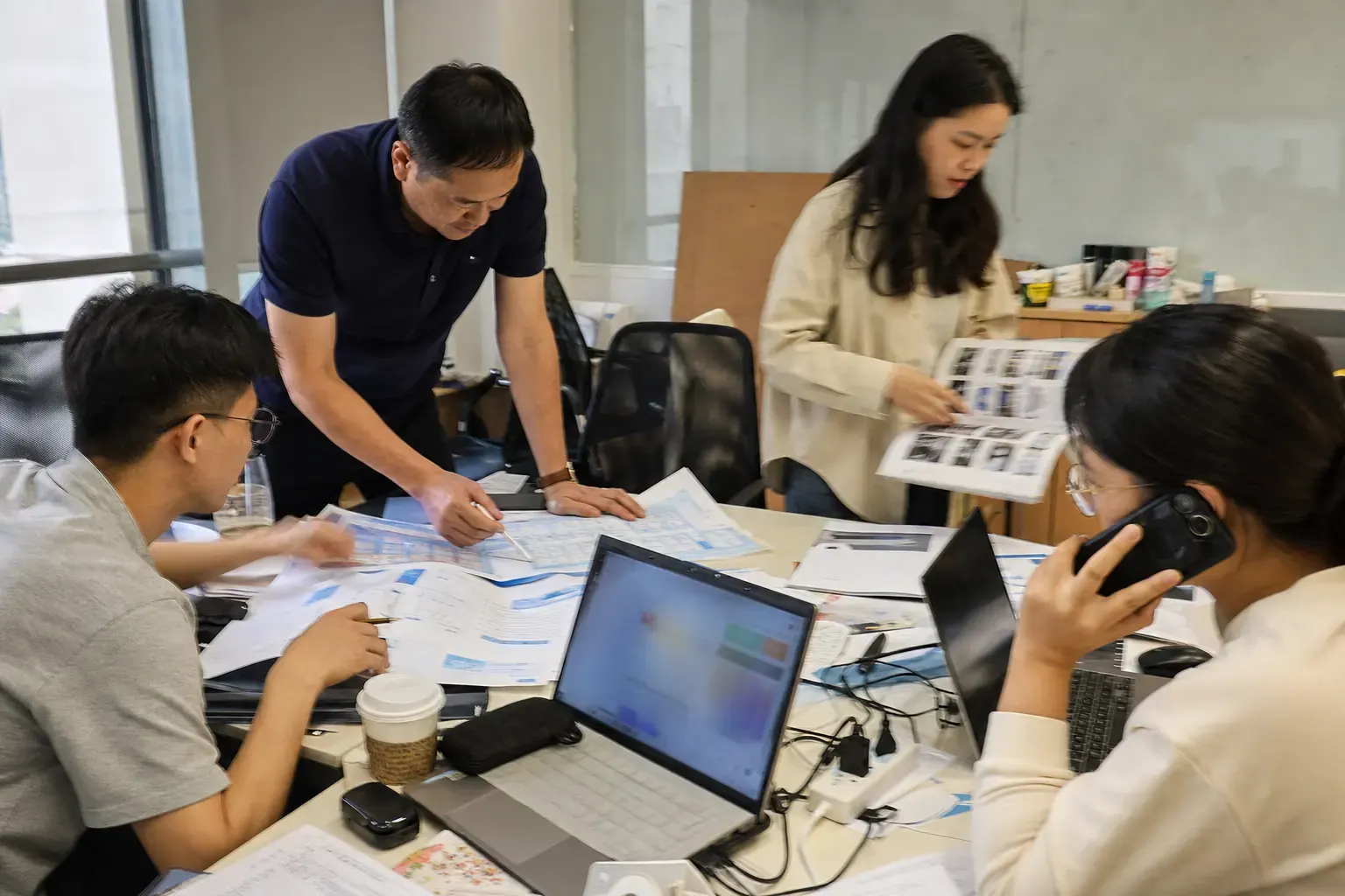 A Chinese export team comparing floor plans and brochures from several overseas trade fairs